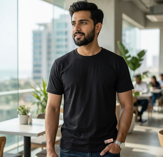Man wearing a Sunnah Conscious black 100% cotton round neck t-shirt in a bright modern office setting.